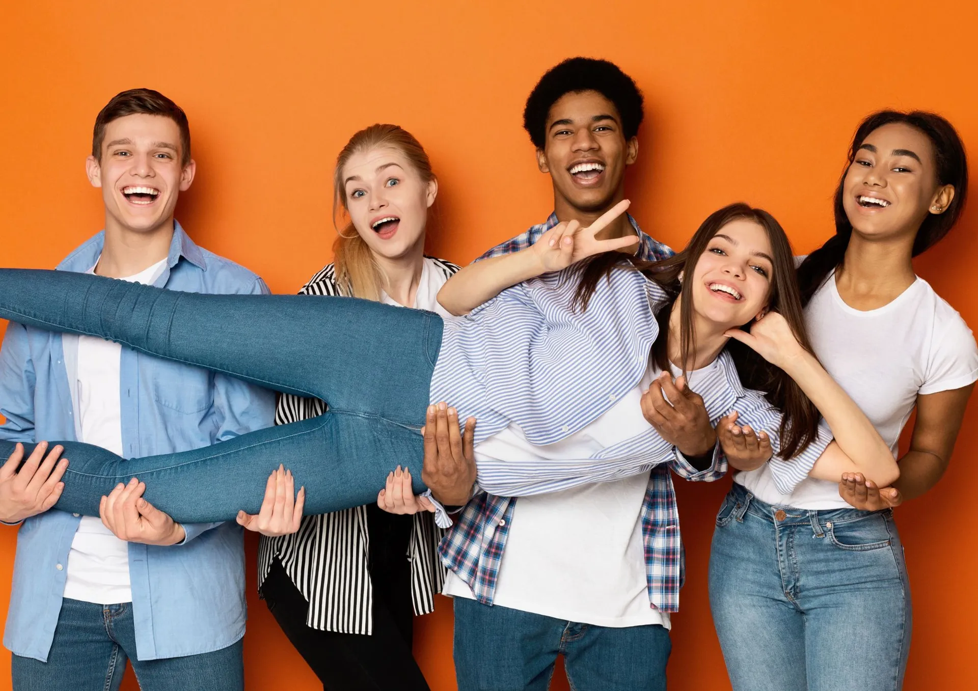 jeune équipe joyeuse portant une collègue dans ses bras sur fond orange, Floorz La Grande Parqueterie recrute près de Strasbourg