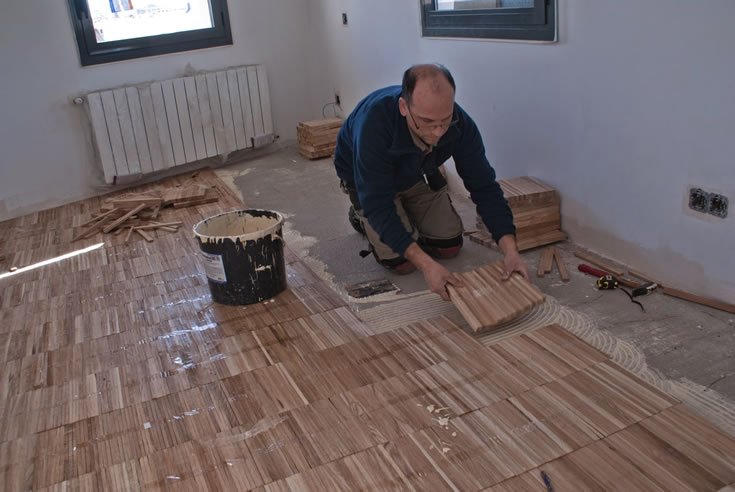 Pose collée d'un parquet industriel sur chants par un poseur Floorz