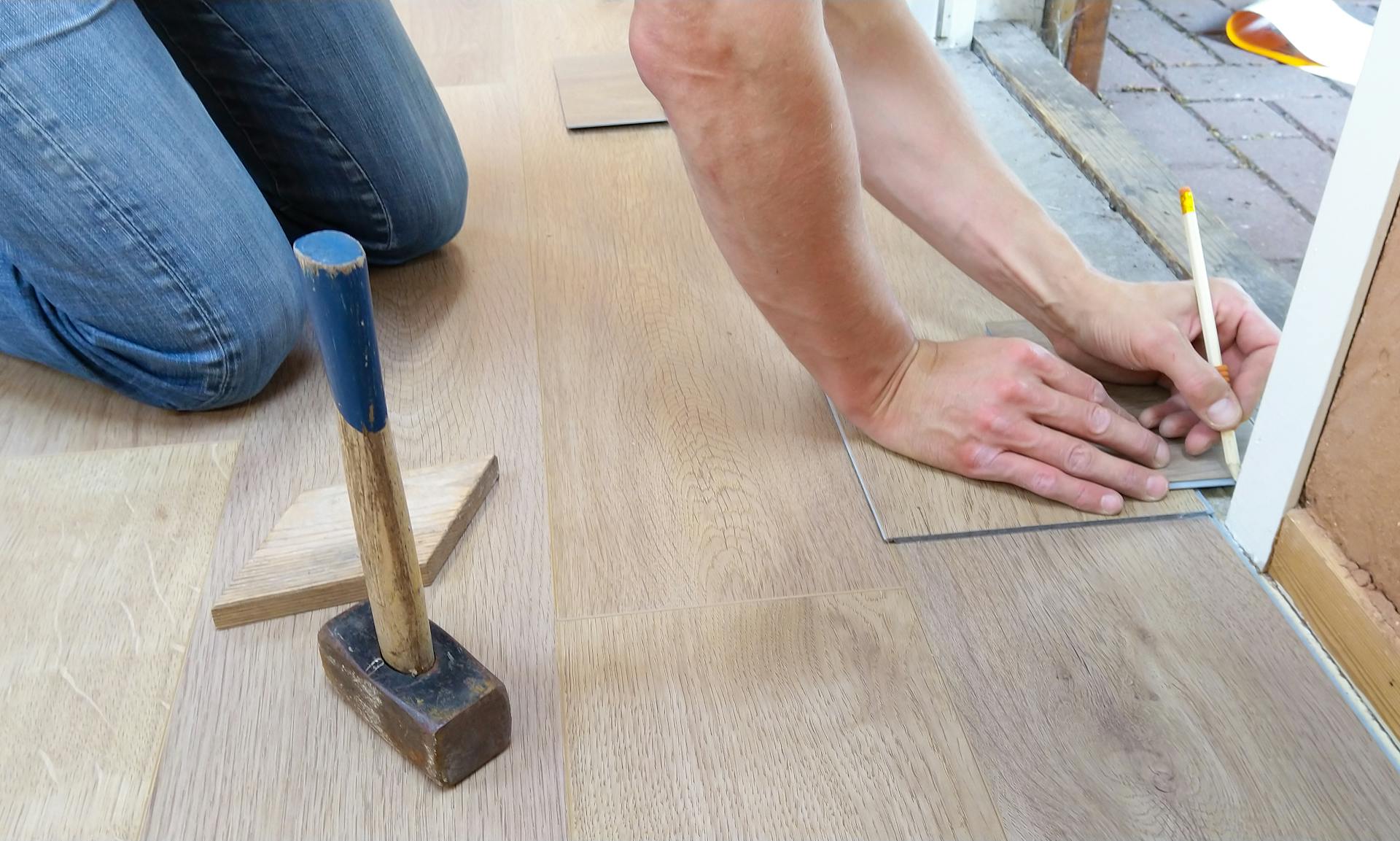 Parquettiste professionnel en train de réaliser une pose de parquet collé sur chantier